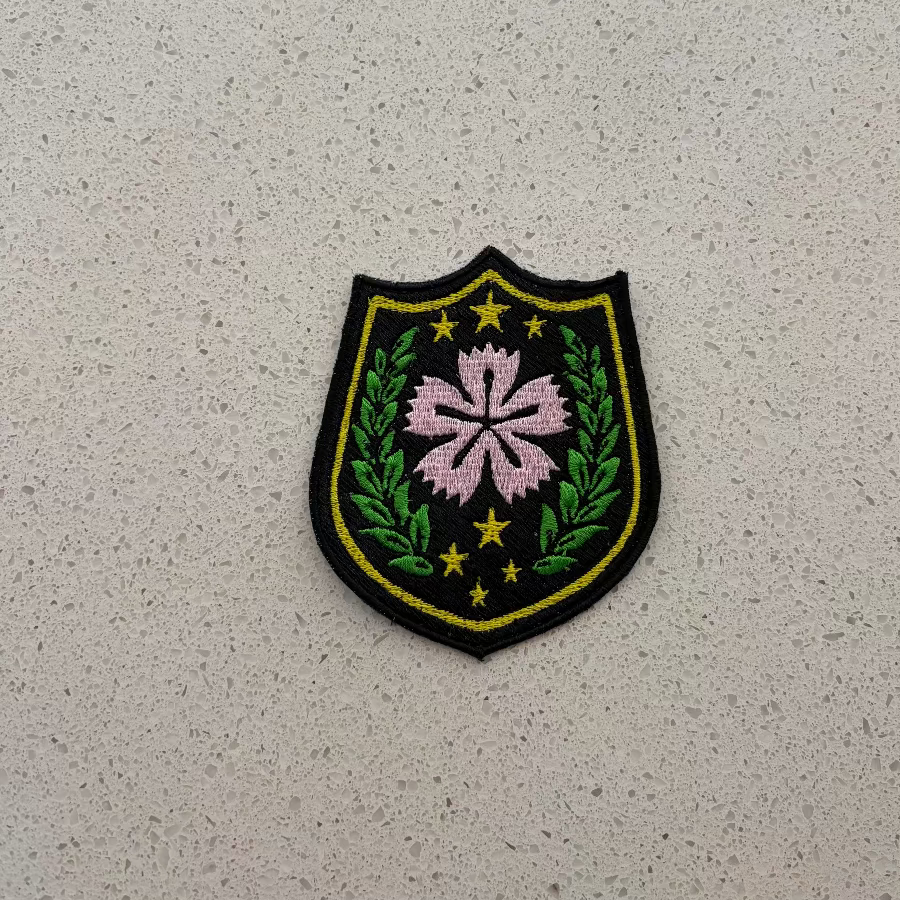 Embroidered patch with floral design and stars on a textured gray background