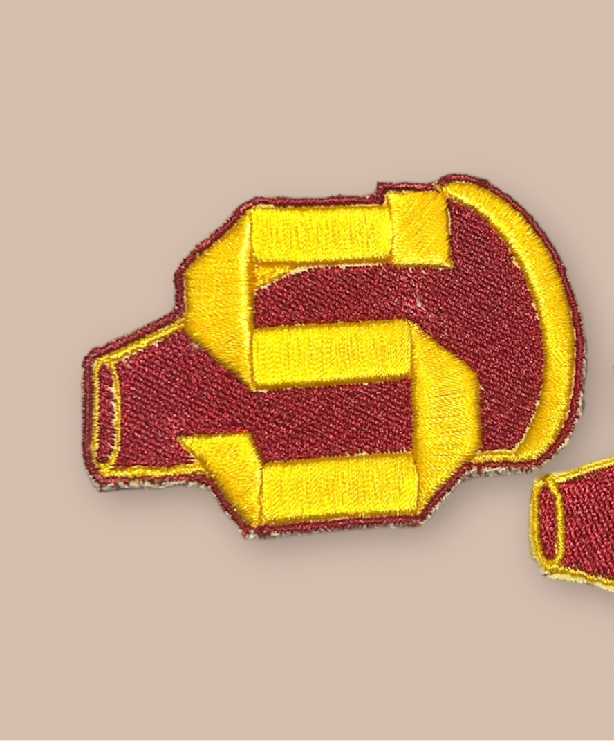 Sunnydale Cheerleader uniform patch, a golden yellow “S” in front of a maroon megaphone