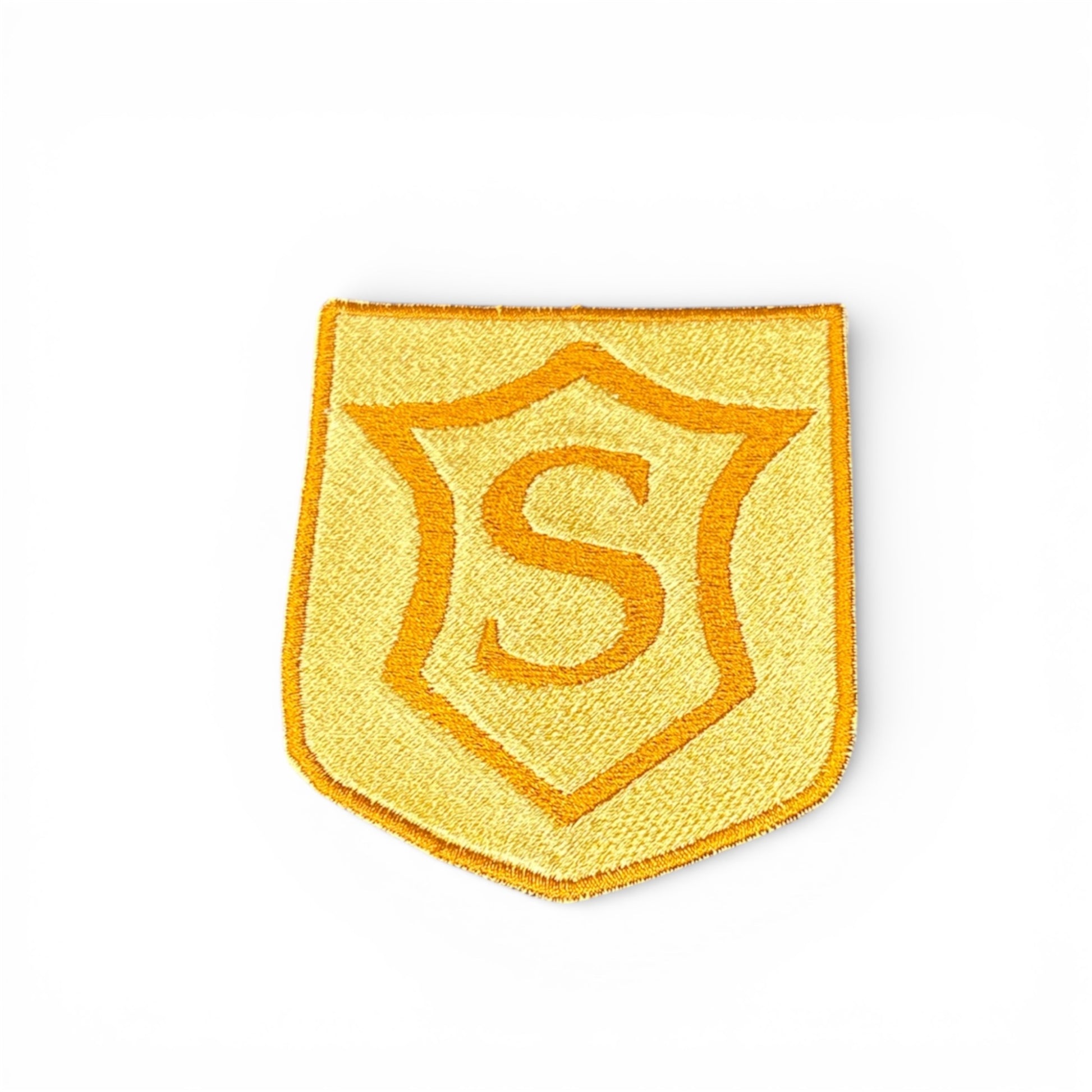Yellow shield shaped patch with an “S” inside of it, surrounded by a more pointed stylized shield