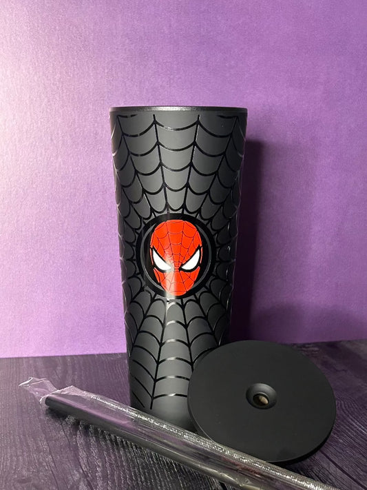 24oz black matte tumbler, with a glossy vinyl of a black spiderweb and red Spiderman mask in the center. To the bottom right is a matching matte black lid, and a straw wrapped in plastic.