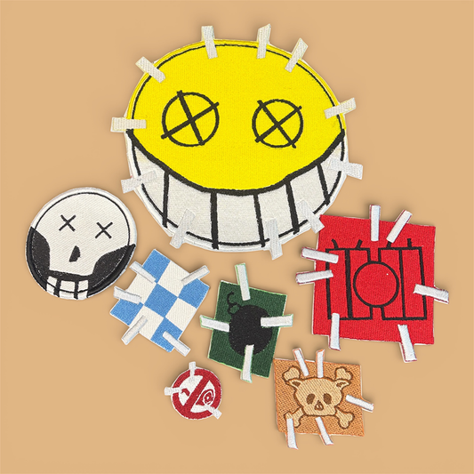 Collection of patches from Junkrat of Overwatch. A large smiley face, black and white skull, blue and white checkered square, green rectangle with black bomb, dynamite sticks on a red background, and what appears to be a skull of a dog with the crossed bones behind it