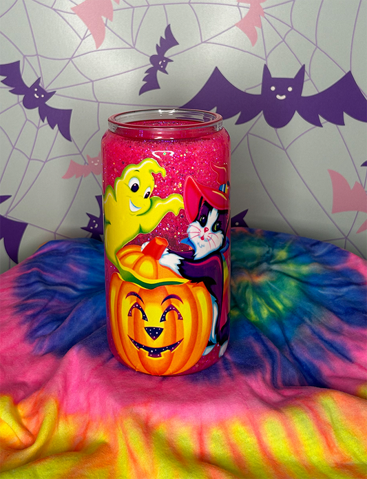Glitter globe cup with neon pink glitter inside, and a decal of a purple cat standing next to a jack o lantern and green ghost coming out of the pumpkin